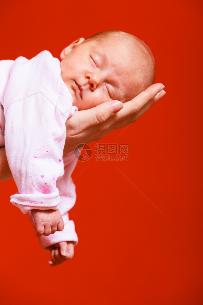 父母亲和爱的概念一个月大的女婴在母亲舒适怀抱红色背景图片