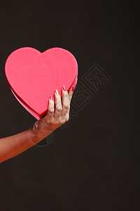 情人节爱浪漫概念女手握心形礼物盒深灰色背景图片