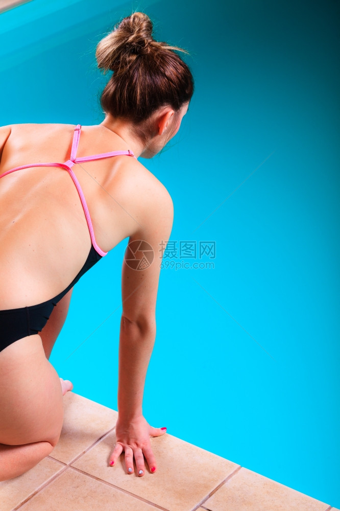 运动型女子游泳运动肌肉健身体准备跳跃和潜入游泳池后视图片