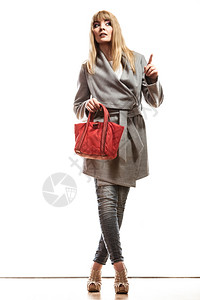 时装和广告饰TFull身女子优雅的灰色皮带外套上面拿着红色手袋指空的间图片
