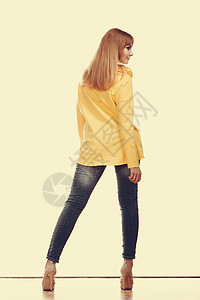 时装和人的概念穿牛仔裤长的女人高跟鞋黄色衬衫背视图片