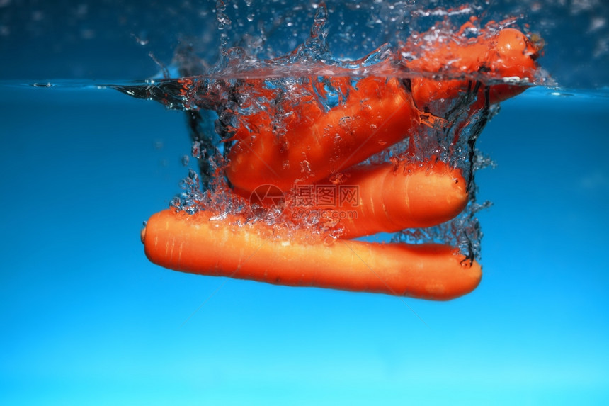 海水中的胡萝卜在蓝色背景上喷洒健康的食物和活生图片