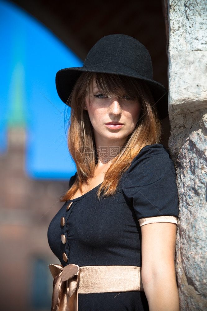 穿黑帽子和着衣的回春时装女孩在旧城欧洲市GdanskDanzigPoland街上图片