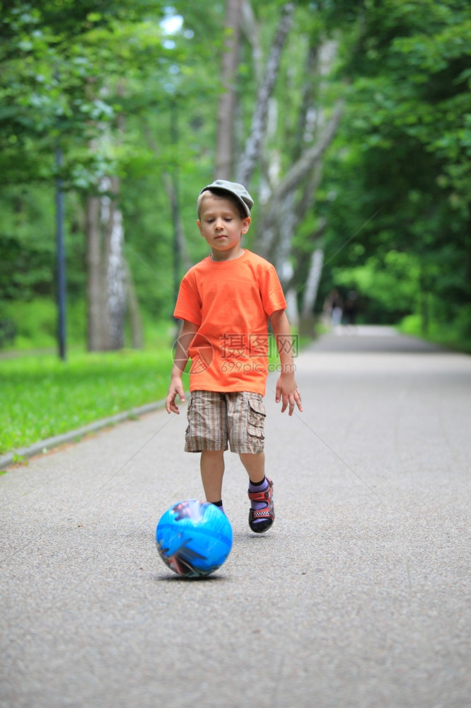 男孩玩球踢在户外公园向球跑图片