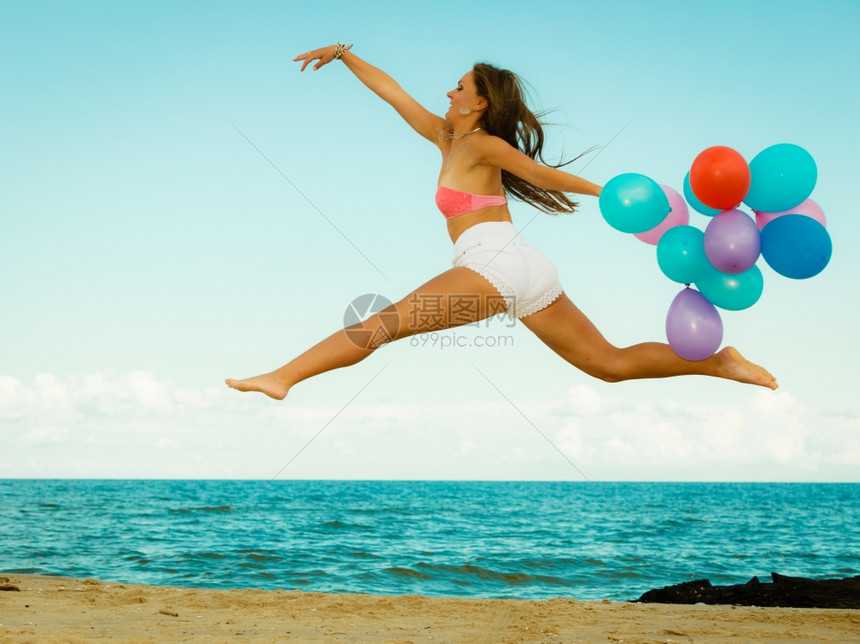暑假庆祝活动和生方式概念美丽的少女孩在海滩上用彩色气球跳出海滩图片
