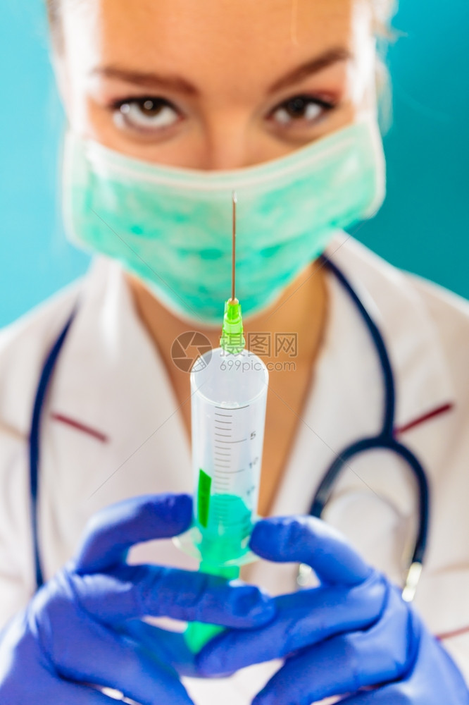 保健和医药概念戴面罩持有注射针筒蓝底器的女医生图片