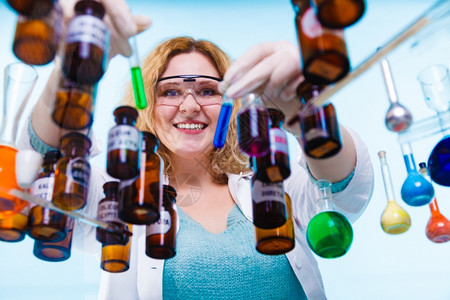 化学女家或生实验室助理或科学研究员在蓝色上装有化学玻璃软件试验瓶图片