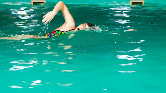 游泳竞争和娱乐女游泳者呼吸时表现的爬行风格游泳池边图片