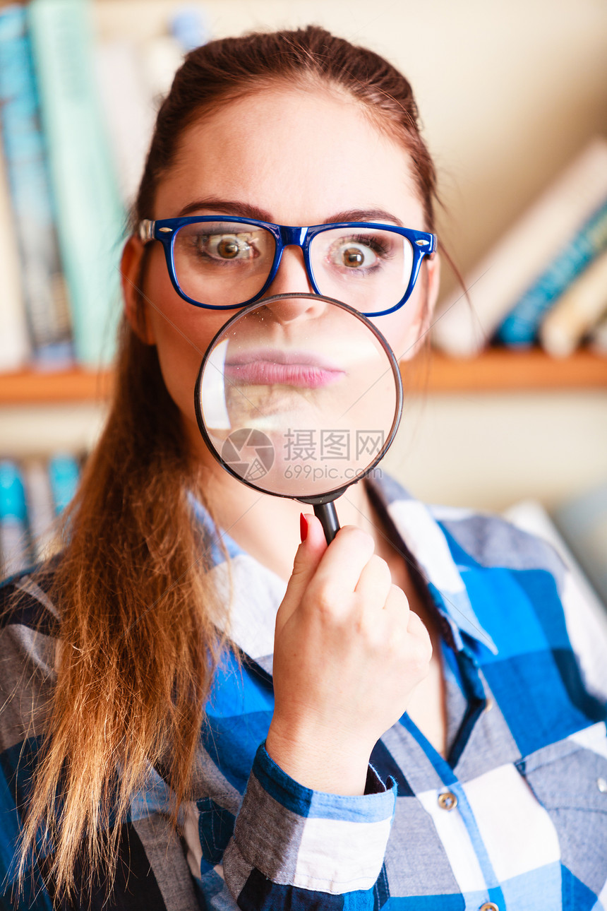 探索教育概念图书馆的特写有趣学生女孩戴眼镜的子拿着放大镜图片