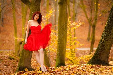 穿着红礼服的全长时尚优雅年轻女子在秋公园散步时户外放松图片