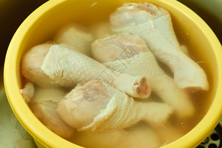 鸡肉加工把生鸡肉腿放在水里洗干净准备食物背景