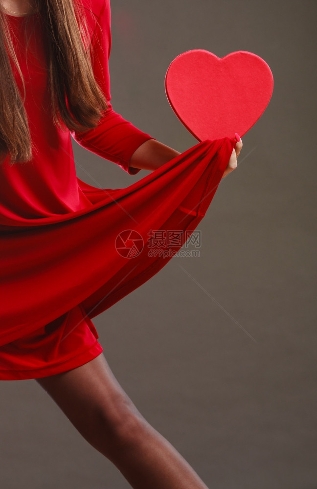 情人日爱浪漫概念穿红裙子的女人拿着心形礼物盒手握深灰色背景图片