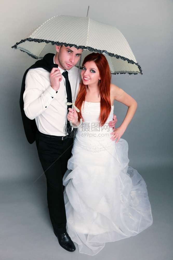 新郎和红发娘的肖像伞式工作室在灰色背景上拍摄图片