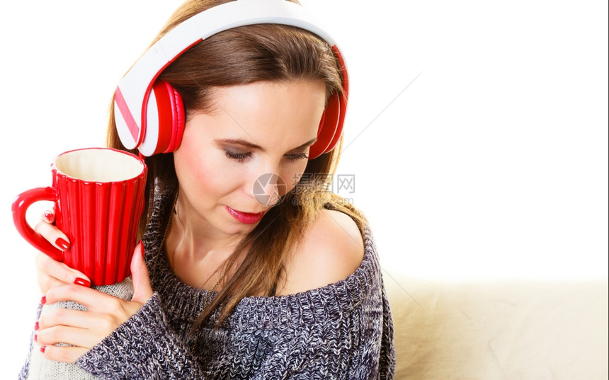妇女随便的红色大耳机听音乐mp3坐在沙发上家里放松图片