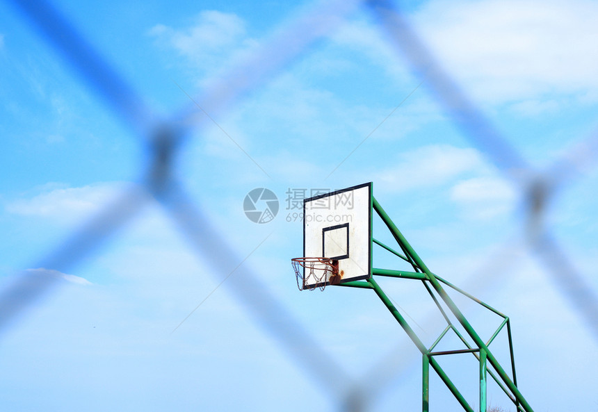 蓝云天背景和模糊金属网铁丝栅栏上的篮子图片