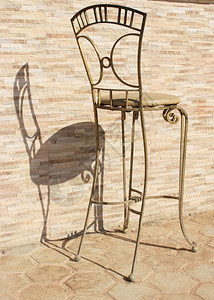 太阳光下的金属椅子旧石头背景的椅子反转投影高清图片