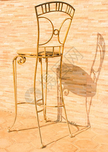太阳光下的金属椅子旧石头背景的椅子反转投影高清图片