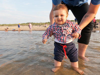 年轻父亲在海水中抱着孩子玩得开心图片