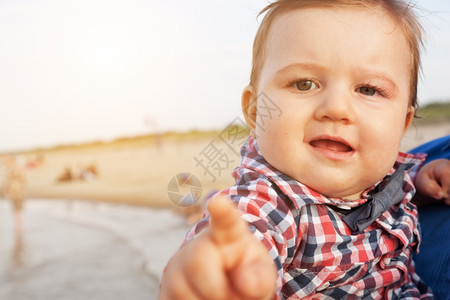 孩子指着摄影机笑的表情被海滩上的父亲抱住图片