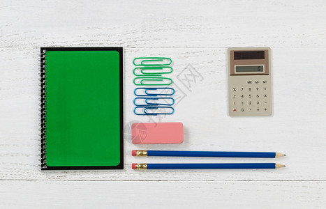 绿色螺旋笔纸上面有铅橡皮计算器和桌面上的纸片图片