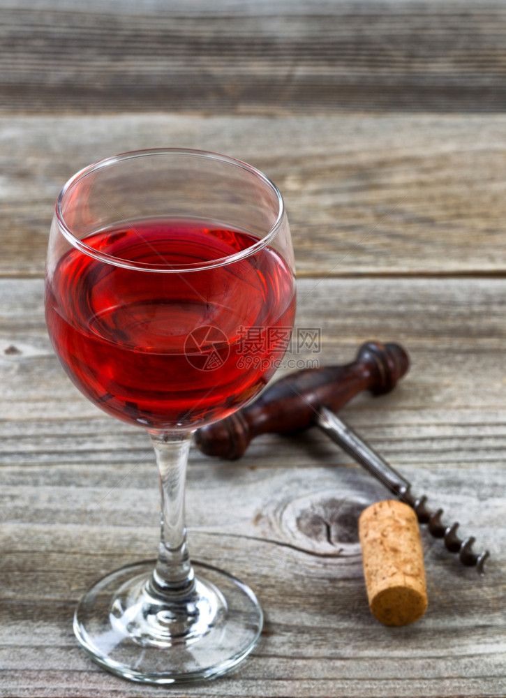 红色葡萄酒的垂直图像以玻璃前唇为焦点古董软木和背景的腐图片