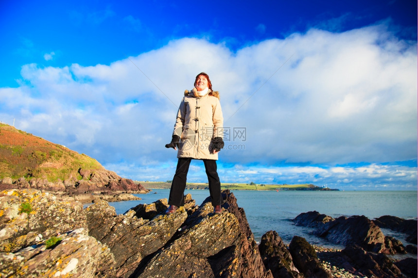 站在悬崖上观大海仰望阳光享受明媚和平放松的女游客图片