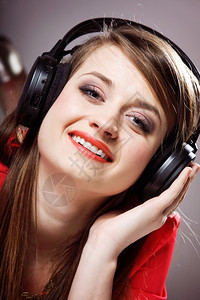 带着耳机的紧贴微笑女孩聆听灰色背景的音乐图片