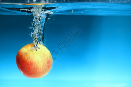 黄色红苹果在水中喷洒蓝色背景上健康的食物和活生图片