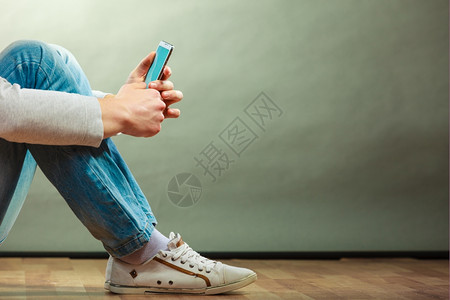 手持机的男子坐在地板上的人使用智能手机复制空间表背景图片