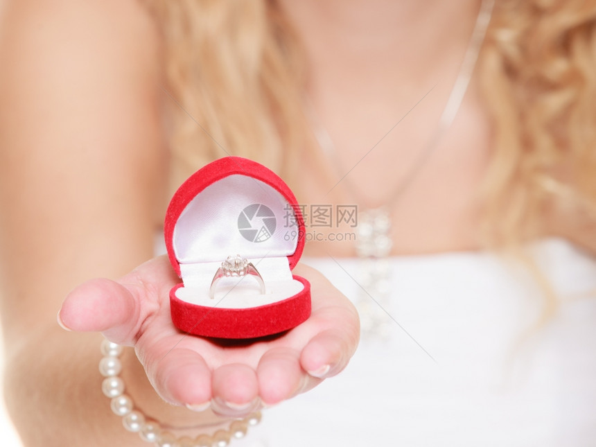 穿着白色礼服的女新娘展示订婚或结戒指红色心形盒子孤立在白色背景上图片