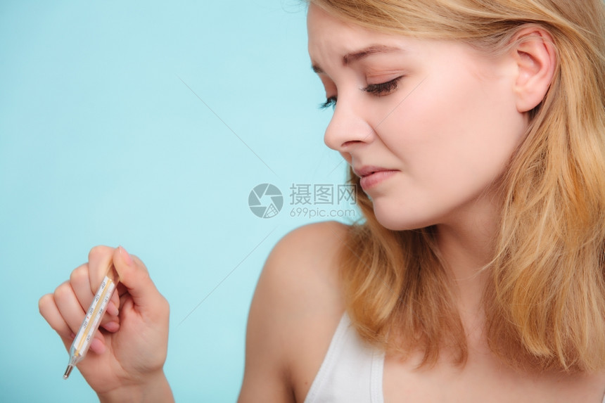 高温女人发烧的病检查蓝色的汞温度计图片