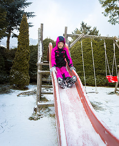 快乐的小女孩在操场上玩滑滑梯图片