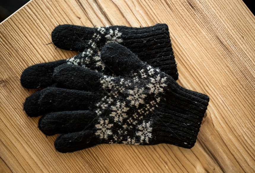 黑色针织手套放在木制桌子上的近照图片