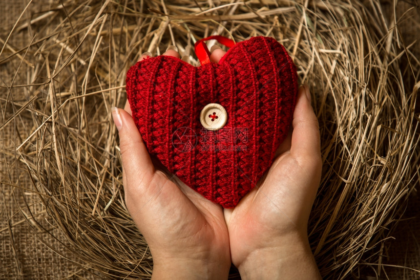 女保护红编织心脏的特写概念照片图片