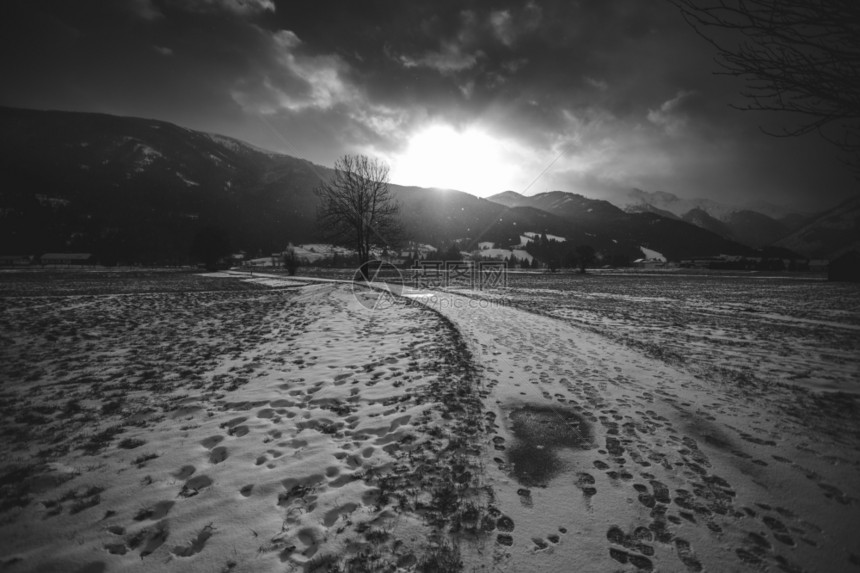 日落时阿尔卑斯山白黑雪路景色图片