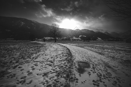 瑞士晨起时日落时阿尔卑斯山白黑雪路景色背景