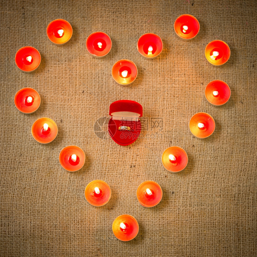 由蜡烛包围的婚礼戒指以心形状的紧贴概念照片图片