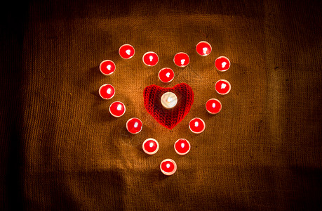 装饰的红蜡烛在麻布上形成心脏状图片