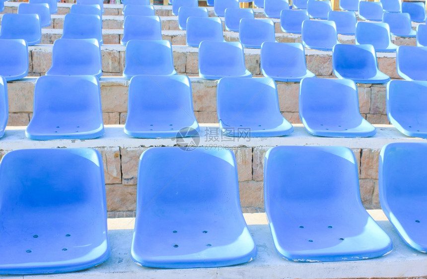 阳光照耀的蓝椅子体育场图片