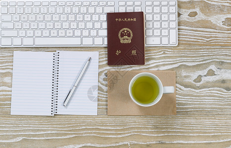 工作桌面护照键盘和绿色茶饮在白木表面横向展示的顶部图片图片