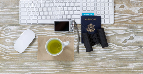 用键盘杯中的绿茶望远镜照相机鼠标和护照横向格式的旧白色桌面顶部视图图片