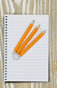 办公室桌面上有三支铅笔上面有旧白木三支纸笔上面有旧白木顶端的视图以垂直格式拍摄背景图片