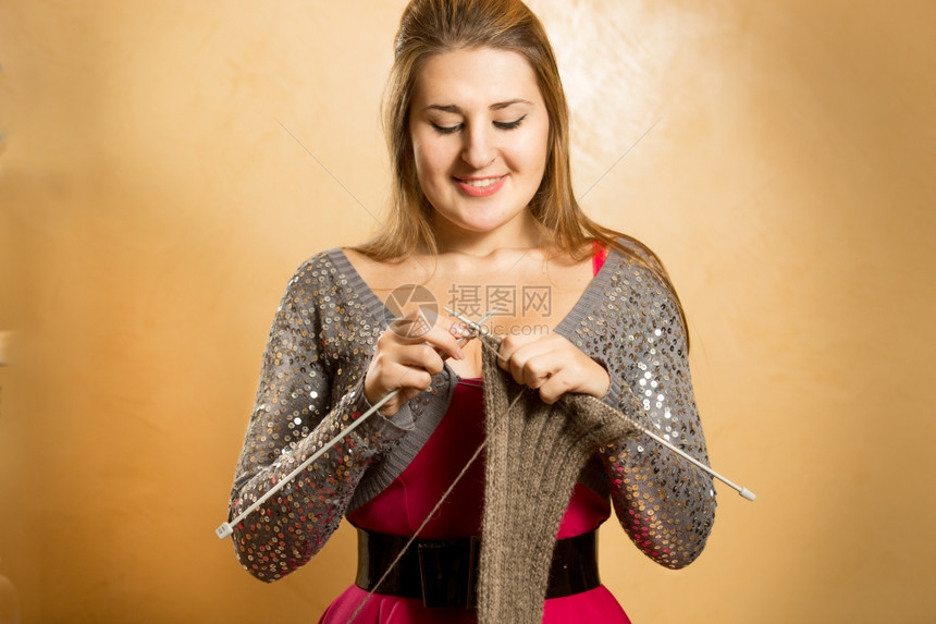 快乐笑的金发女人用针头织围巾图片