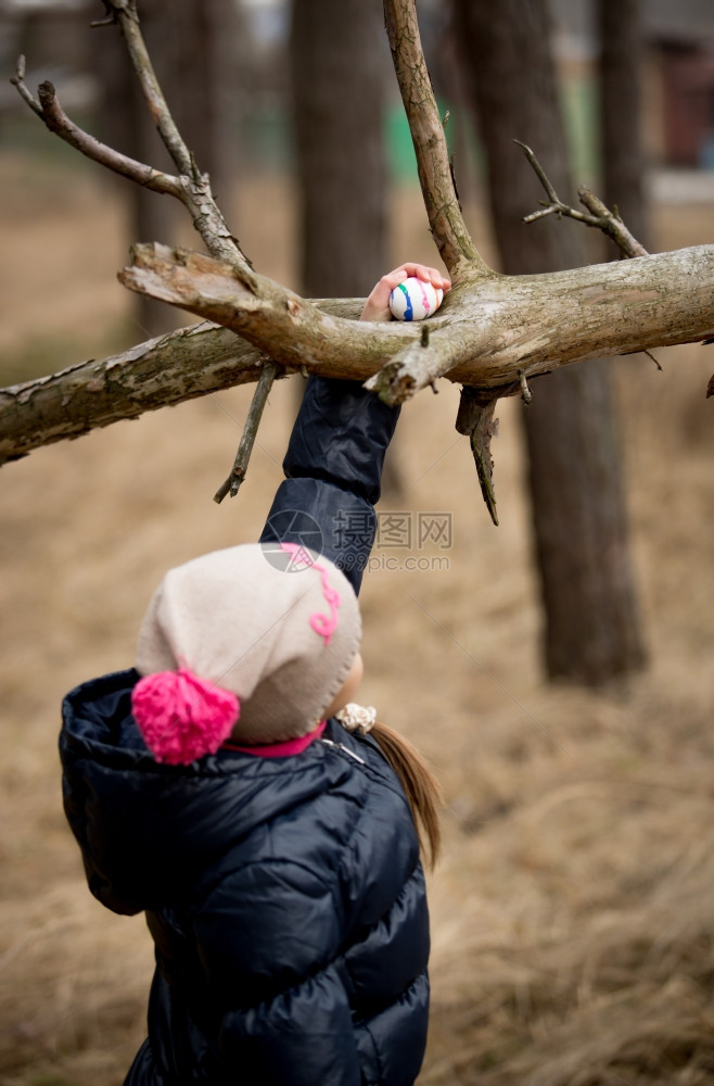 小女孩在高树枝上寻找复活节彩蛋图片