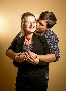 英俊的年轻男人拥抱女友背亲吻脸颊图片