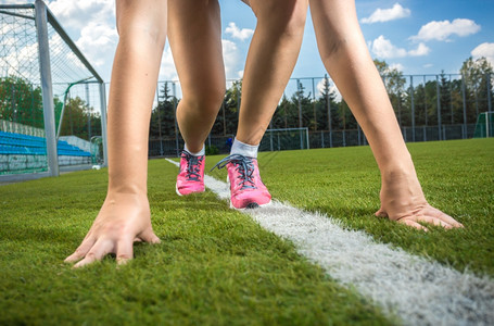 近距离拍摄苗健运动的女人准备在草道上奔跑图片