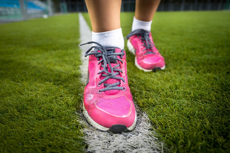 穿粉红色运动鞋跑在新鲜草地上的女人近距离拍摄图片