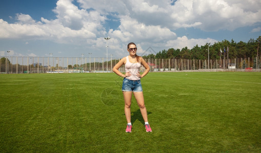 美丽的瘦女人在阳光明媚的日子站在足球场上图片