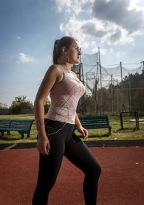 美丽的瘦女人肖像在炎热阳光天气在体育赛场上慢跑图片