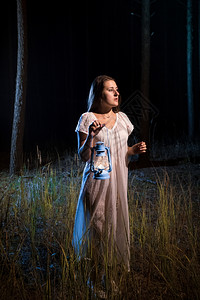 夜里孤单的迷失在森林中女人带着蜡烛的灯笼在森林中行走图片